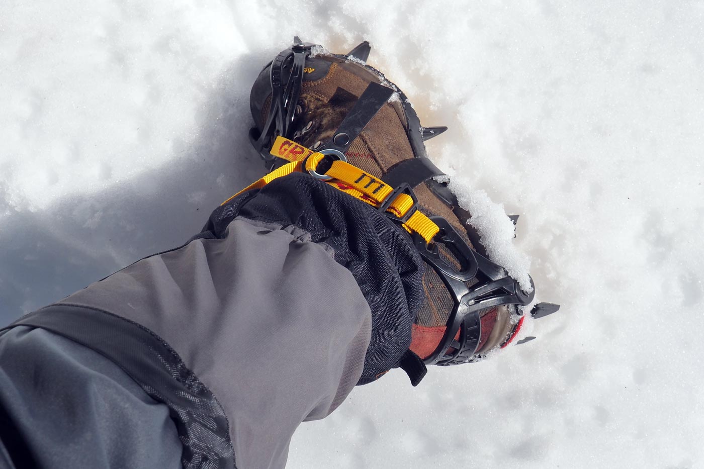 Strap-on crampons correctly fitted to a hiking boot on firm winter snow