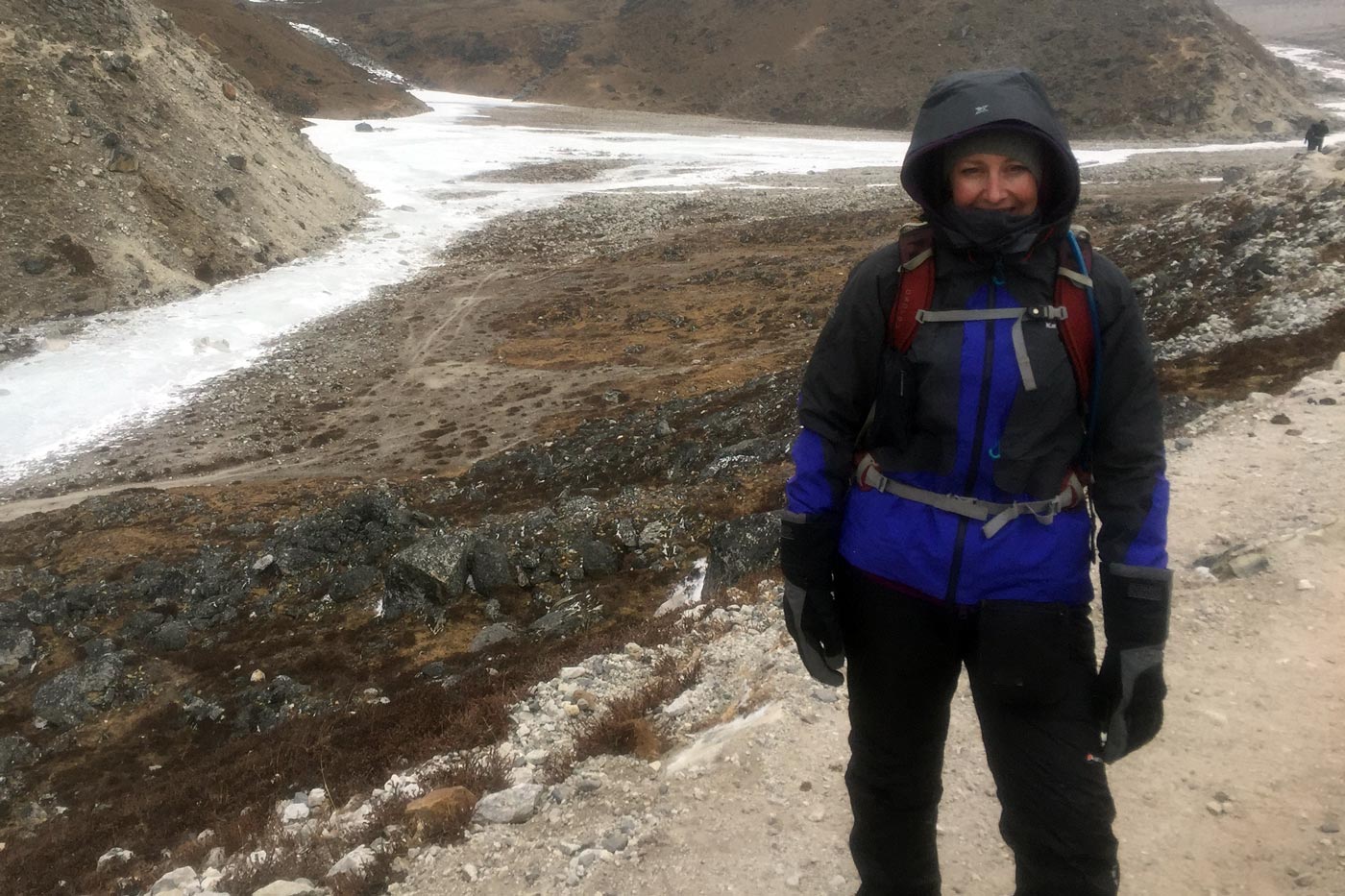 Hiker wearing insulated winter gloves in cold alpine conditions with snow and sleet on the ground