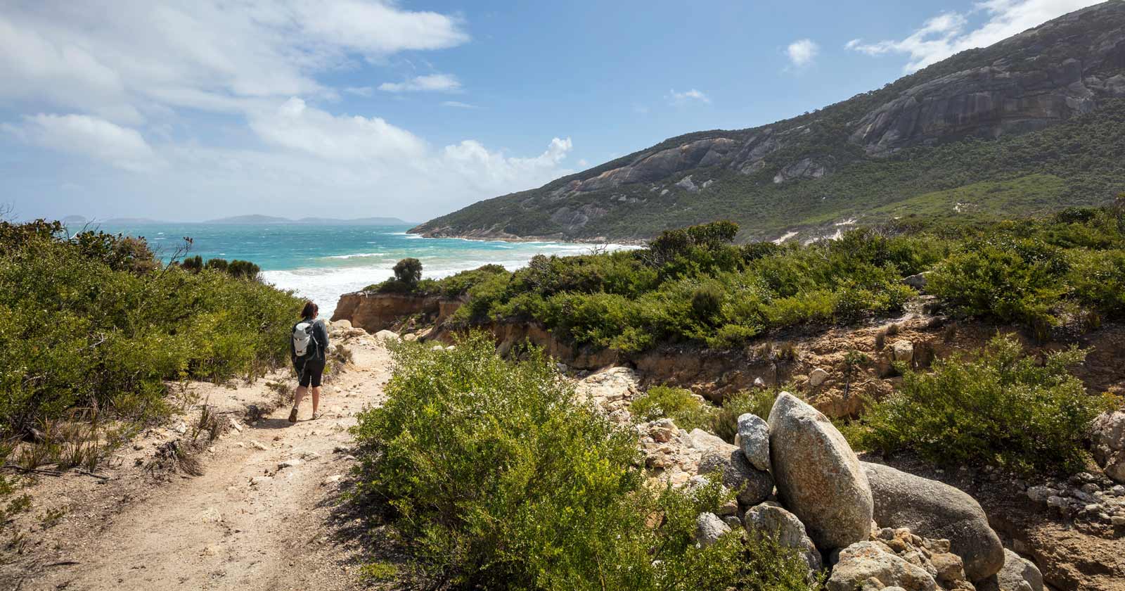 Image of female hiker walking on track to beach