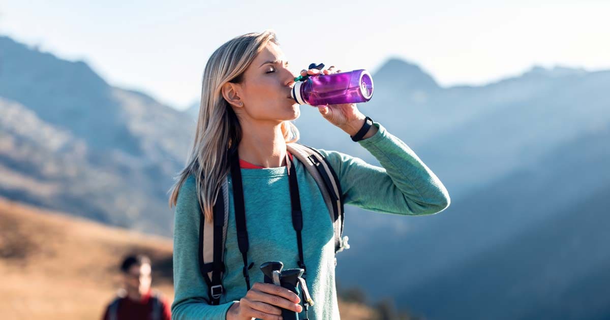 Hiker drinking water on a mountain trail during a multi-day hike