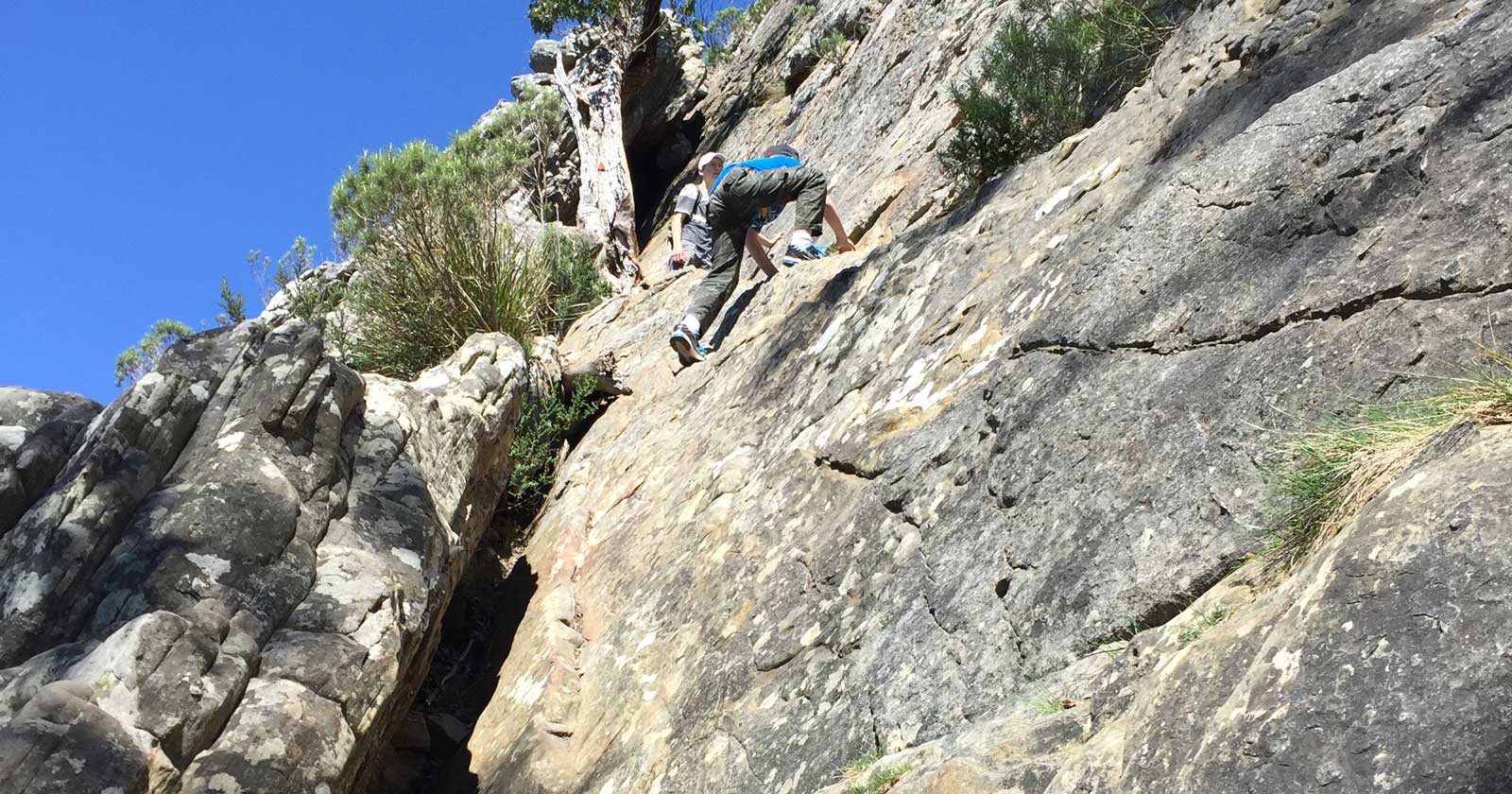 The Psychology Behind Risky Hiking Decisions Hikers scaling near vertical rock slab