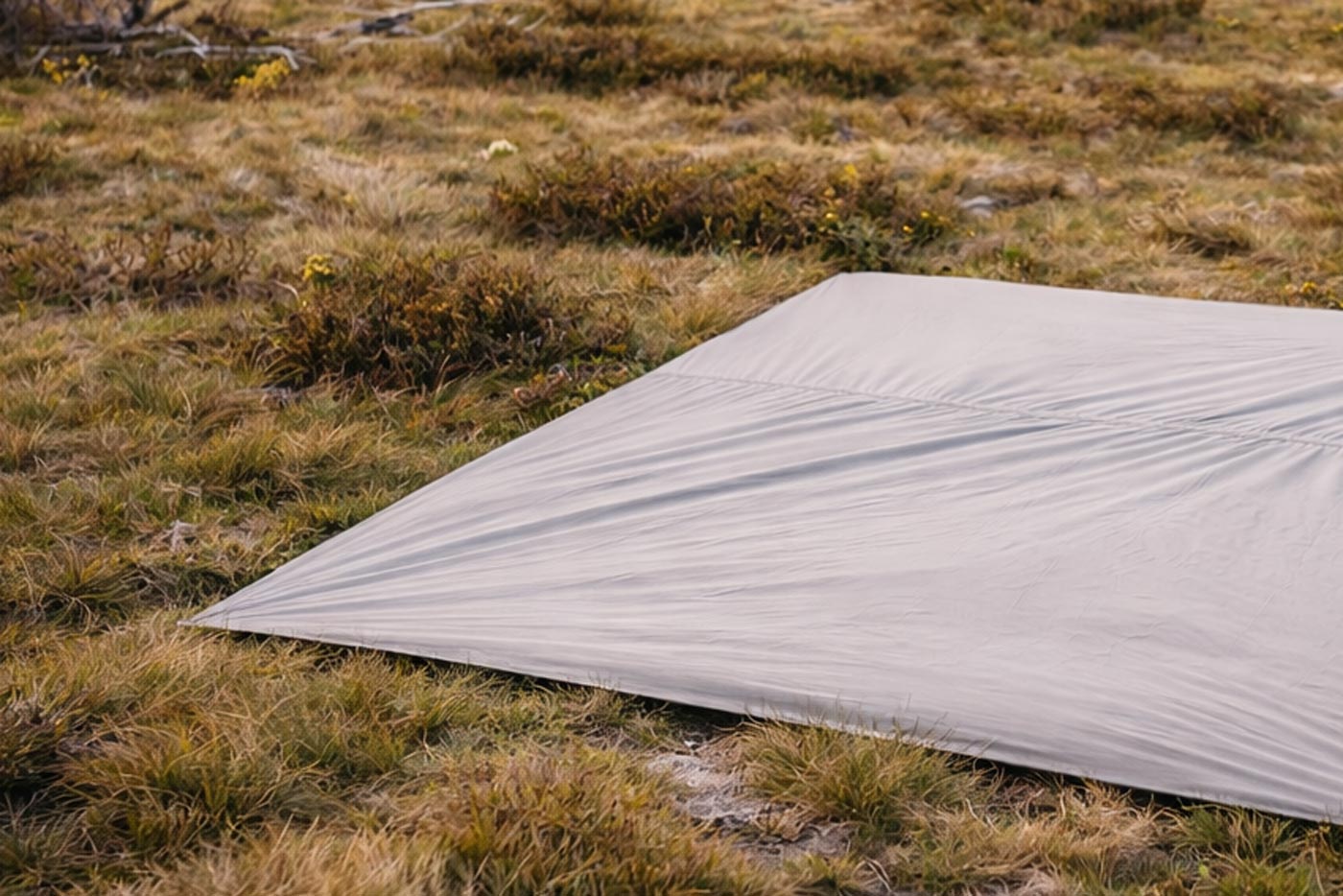 A lightweight groundsheet laid on grass to protect a tent floor from moisture and abrasion.