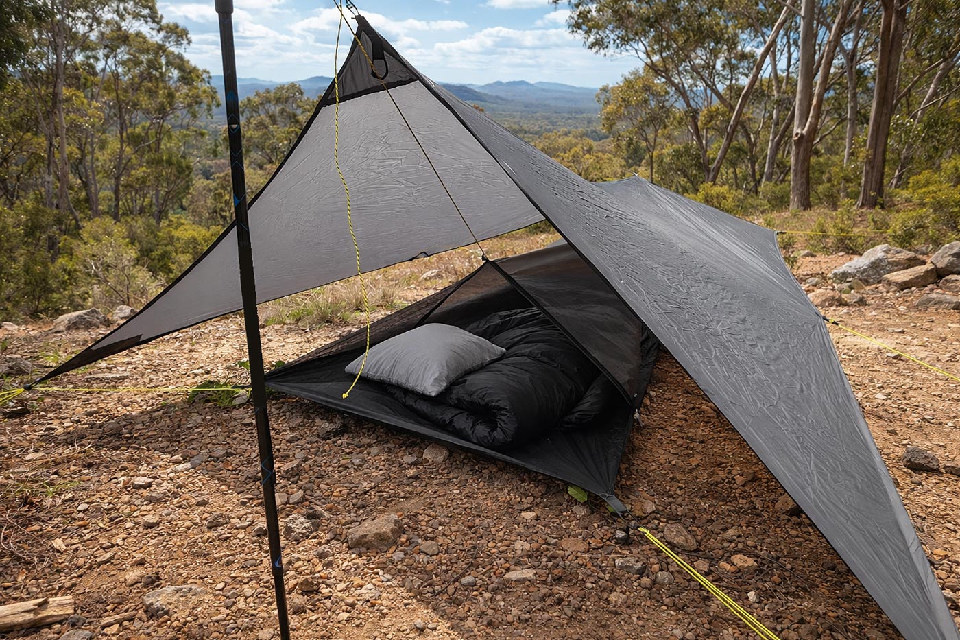 Tarp-style hiking shelter pitched with trekking poles over a sleeping setup on rocky ground, showing an open-sided minimalist shelter.