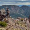 Hiker standing on rocky ridgeline in the victorian high country overlooking layered spurs and valleys