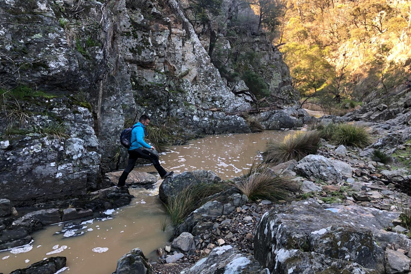 Darren edwards stepping across rocks in a rocky creek gorge in victoria