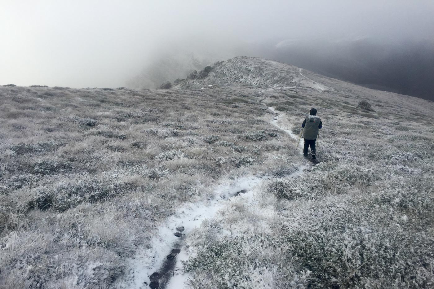 Darren edwards hiking alone on a snow covered alpine ridgeline in low cloud