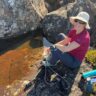 Hiker filtering water from a rock pool on a remote hike