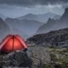 Alpine campsite with glowing red tent at dusk