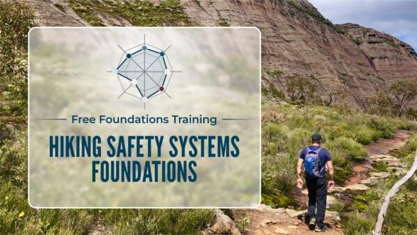 Hiker walking below a rocky ridge in australian bush, looking at the route ahead across rugged terrain