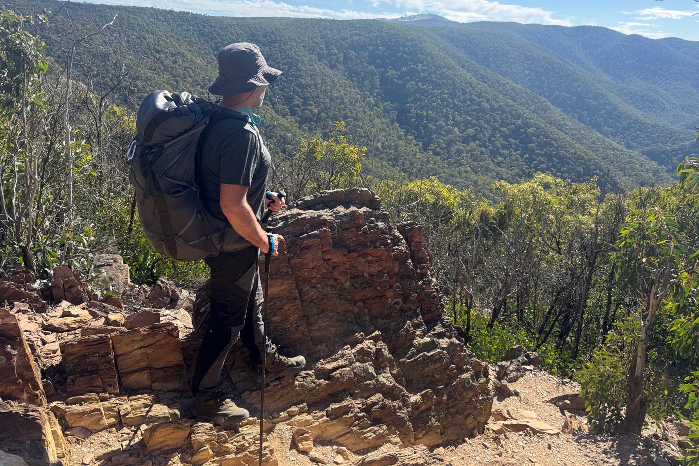 Hiker wearing the north face offtrail hike lt mid gore-tex boots standing on rocky ridge overlooking forested valley