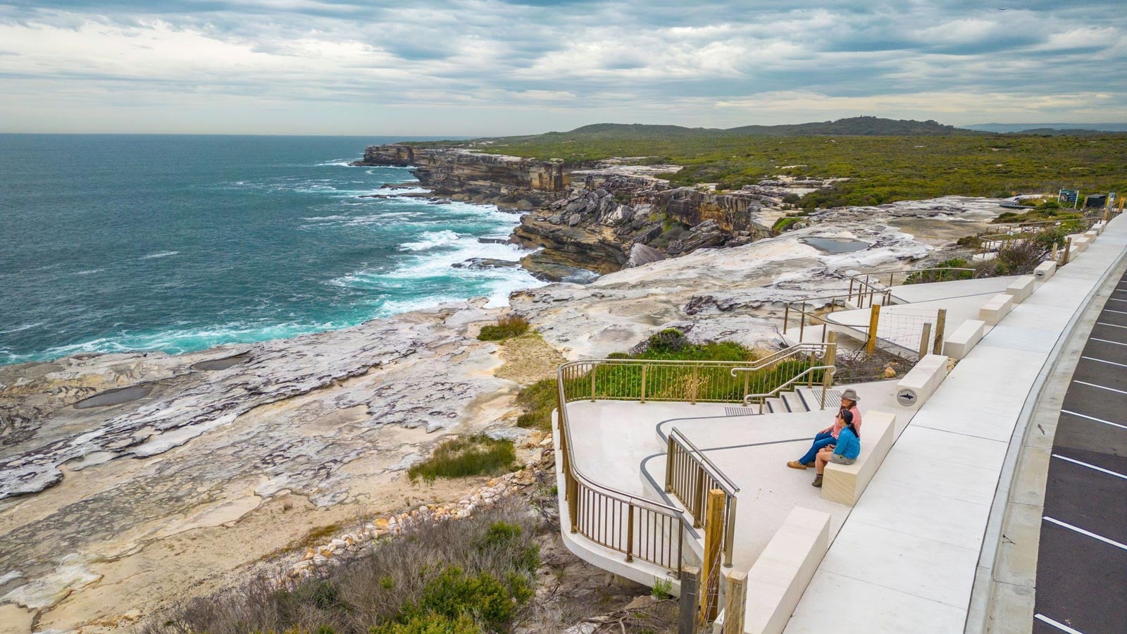 The Hiker's Guide to Whale Watching in NSW Couple sitting at cape solander whale watching lookout on the cape baily walking track, kamay botany bay national park