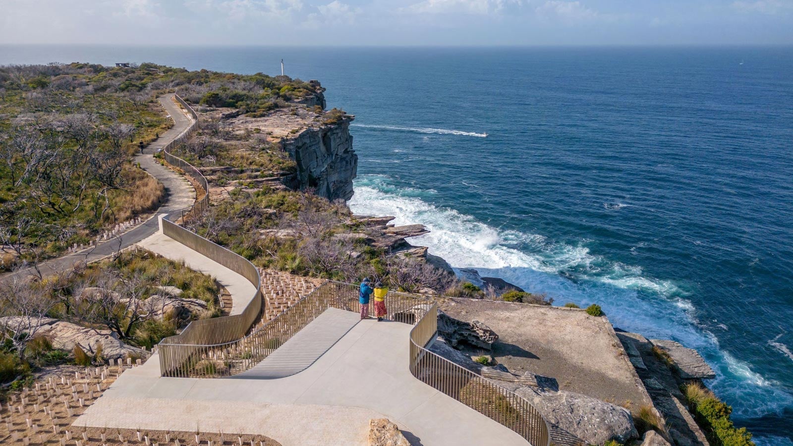The Hiker's Guide to Whale Watching in NSW Two walkers at the burragula lookout on fairfax walk, north head, with dramatic cliffs and open ocean views