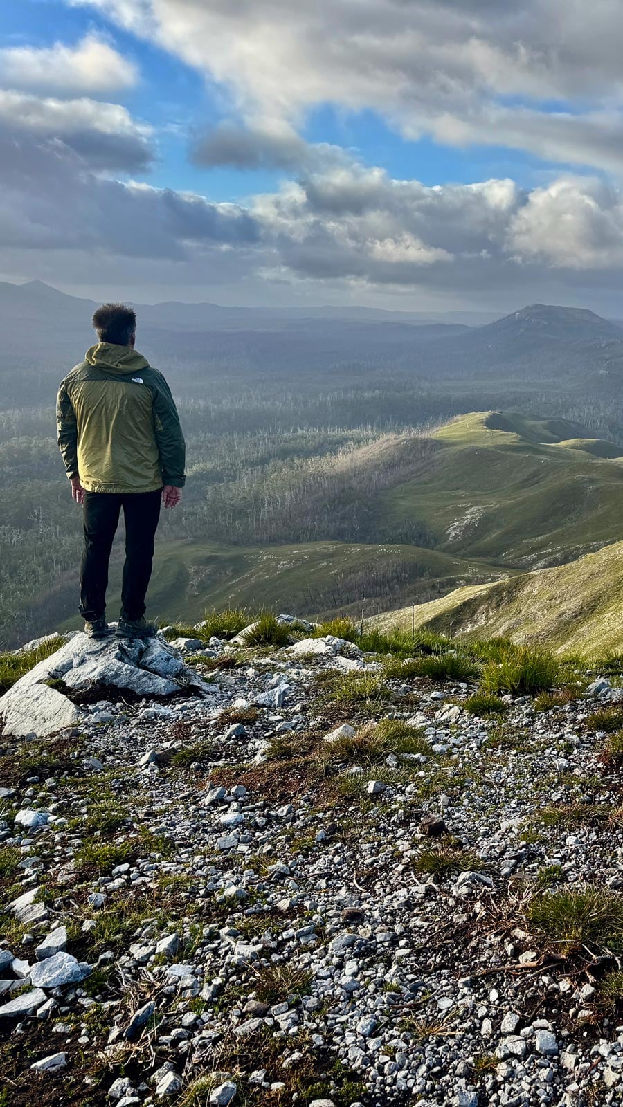 Person standing on the rocky summit of mount donaldson overlooking the vast takayna/tarkine wilderness in tasmania’s pieman river state reserve.
