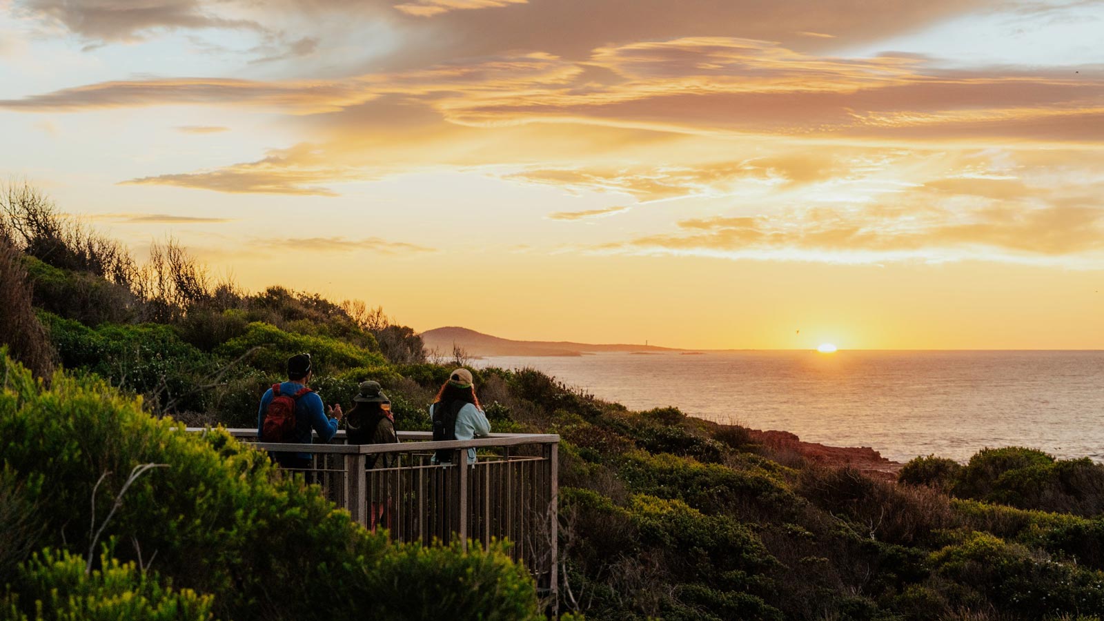The Hiker's Guide to Whale Watching in NSW Three hikers watching the sunset from a coastal lookout on the tomaree coastal walk, port stephens