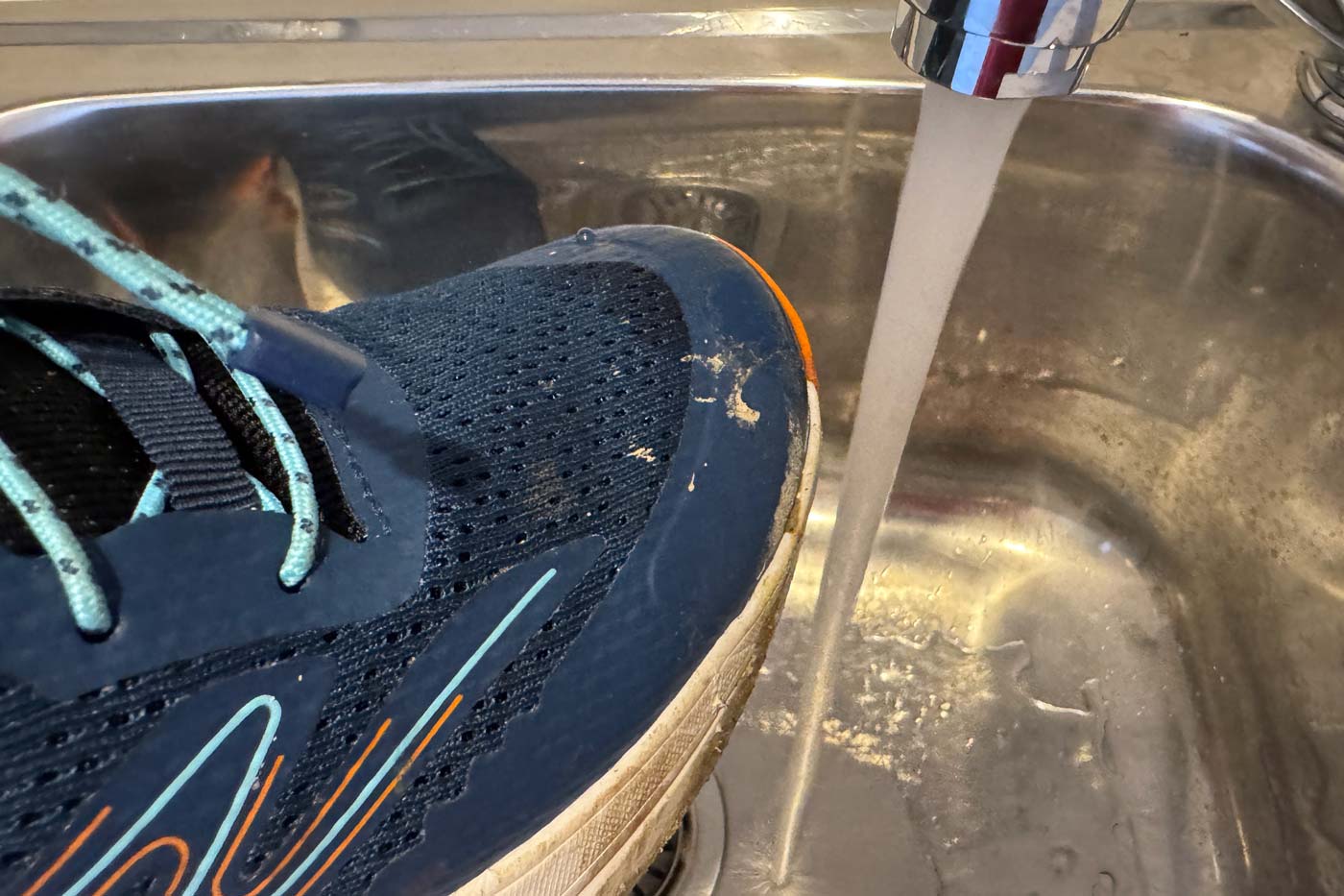 Teva Hurricane Trailsetter Shoe Review Teva men's hurricane trailsetter trail shoe being rinsed under a tap in a kitchen sink after a hike, showing how easily the breathable mesh upper cleans up with water.