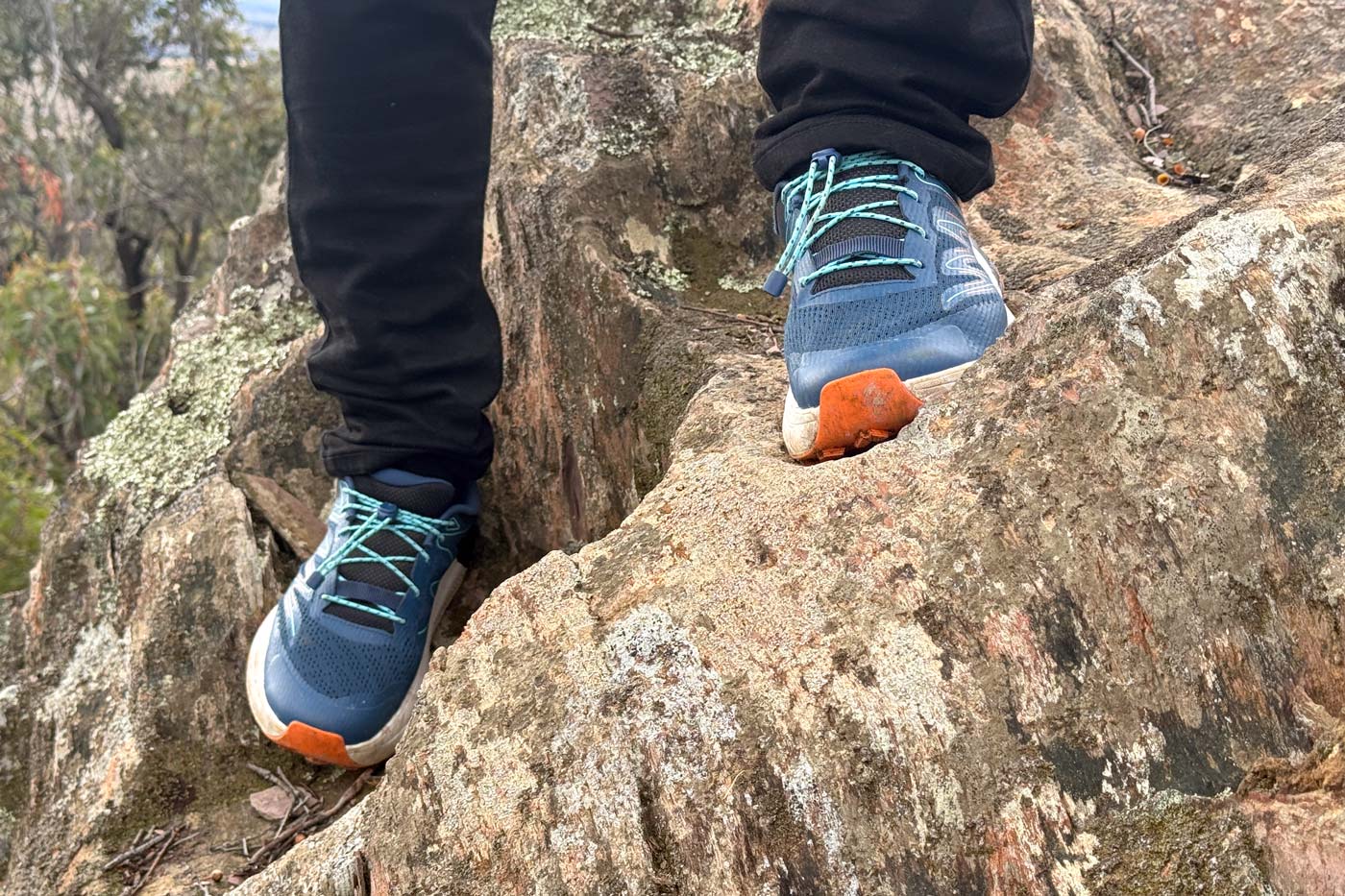 Teva Hurricane Trailsetter Shoe Review Hiker standing on a large granite boulder wearing teva men's hurricane trailsetter trail shoes, demonstrating the shoe's grip and stability on rocky terrain during a field test hike.