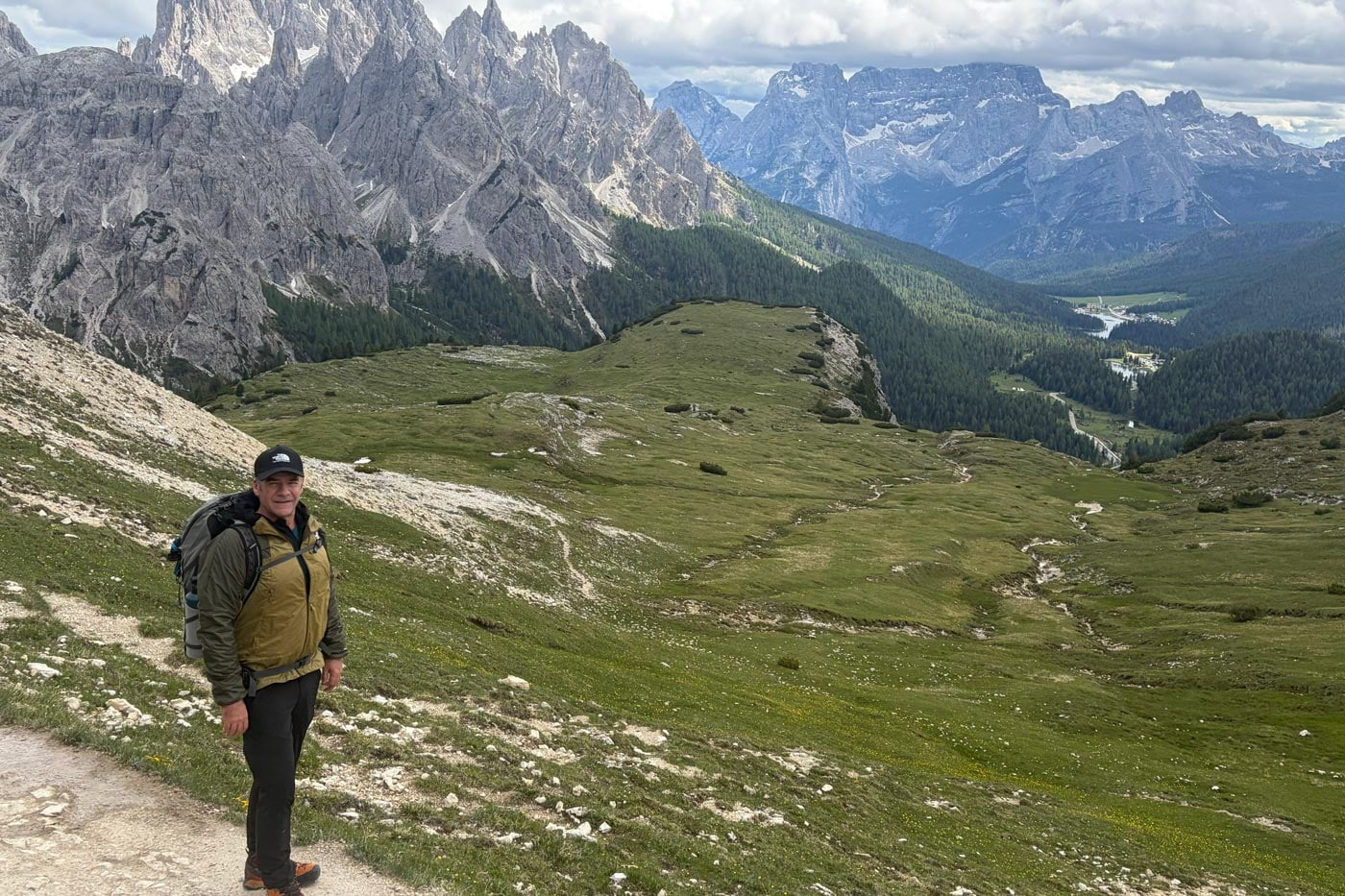 Hiker wearing a ridgelite futurefleece wind jacket stands on a mountain trail overlooking expansive alpine valleys and rugged dolomite peaks.