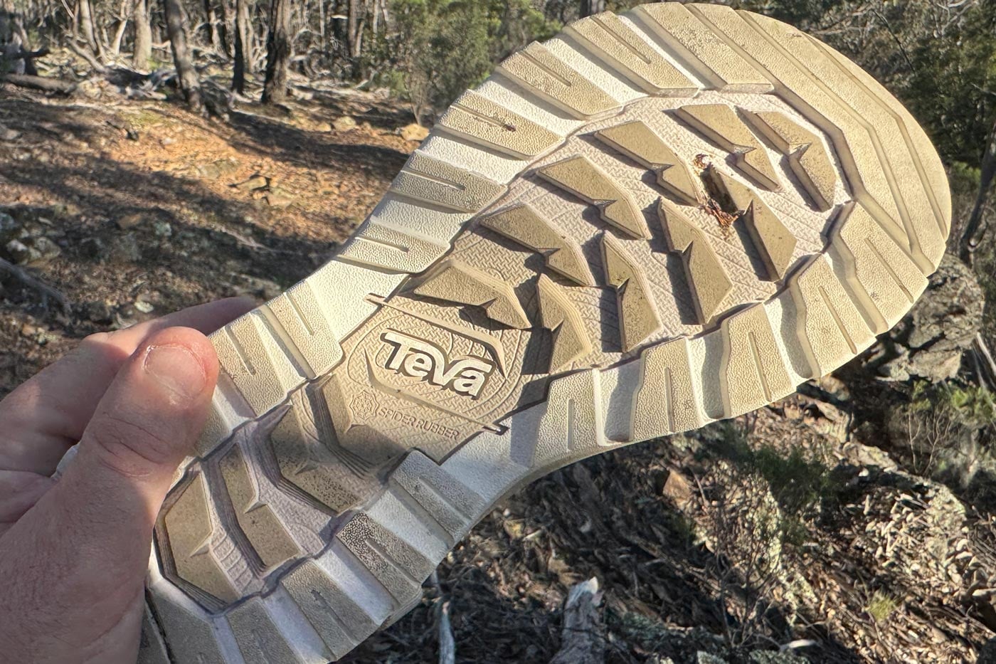 Teva Women's Hurricane XLT3 Sandal Review Hand holding a detached teva shoe sole with spider rubber tread, showing the outsole separated from the shoe in bushland