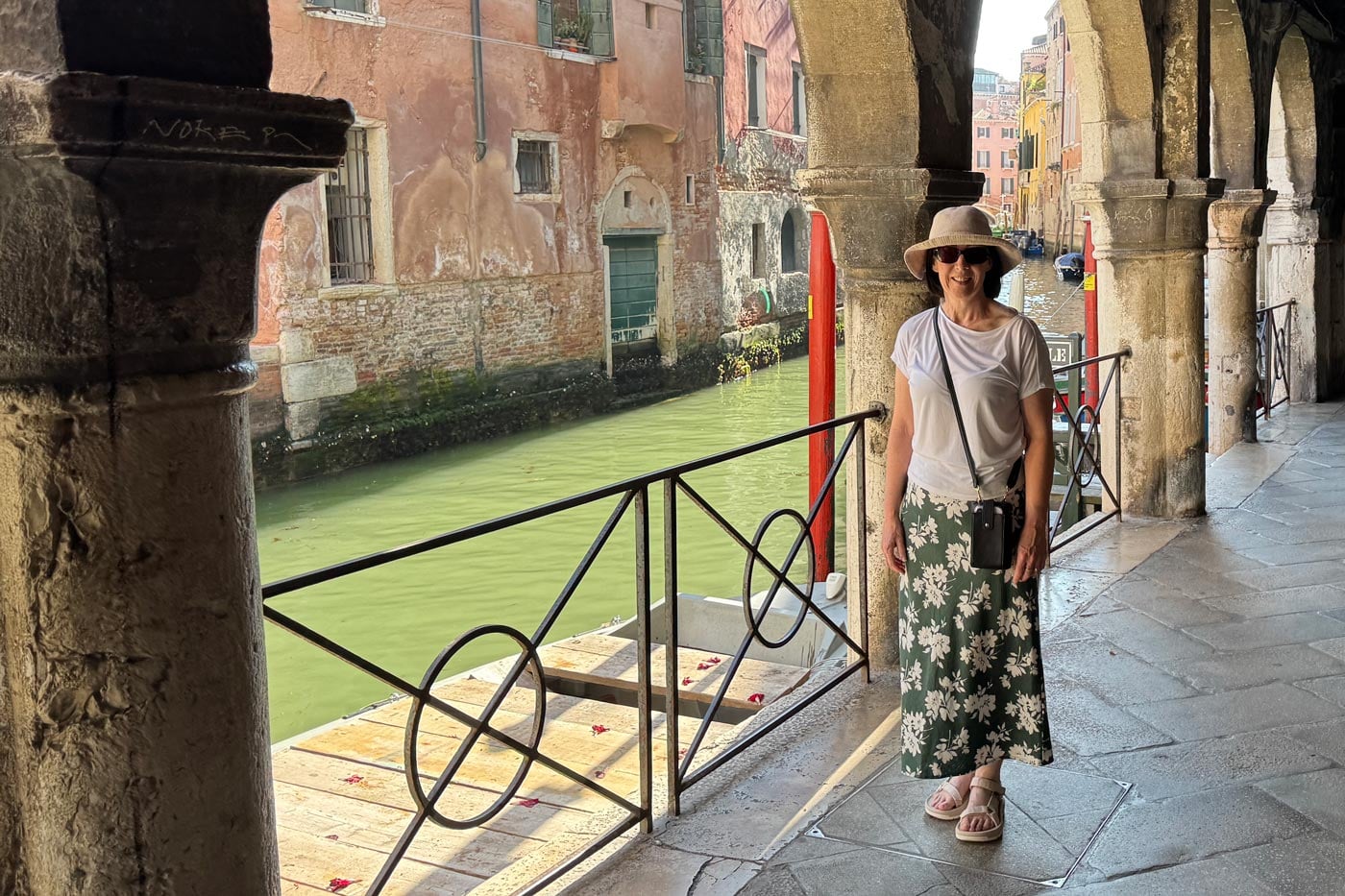 Teva Women's Hurricane XLT3 Sandal Review Woman in a sun hat and floral skirt standing beside a venetian canal under a stone archway