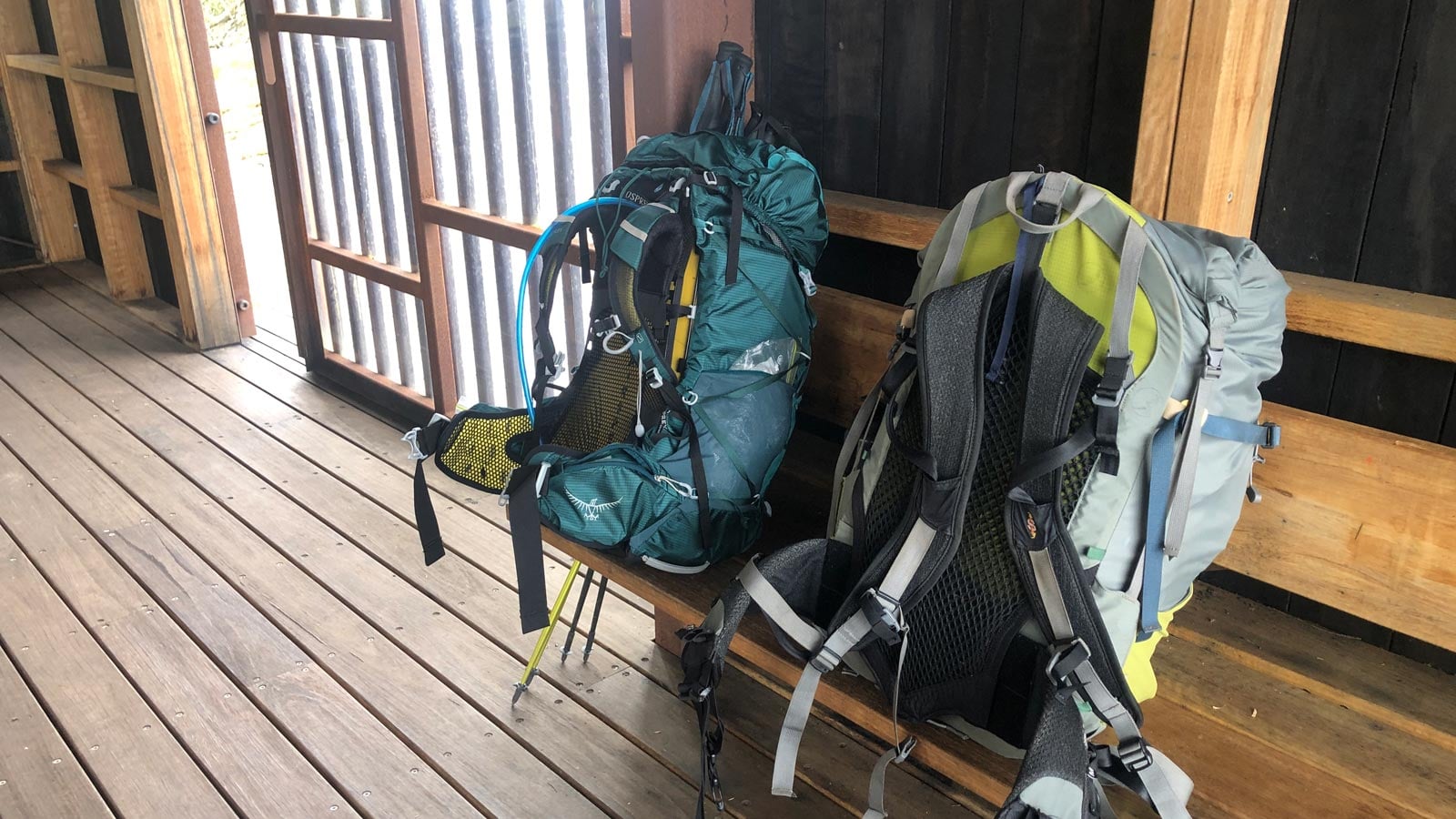How to Keep Your Gear and Vehicle Secure While Hiking Two hiking backpacks with hydration tubes resting on a bench inside a timber hut shelter