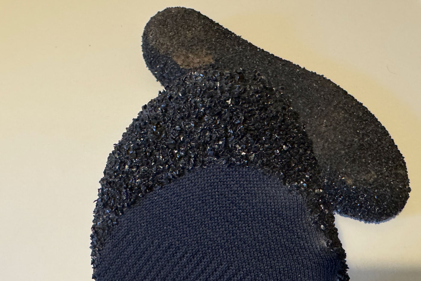 Skinners Comfort 2.0 Sock Shoe Review Close-up of a navy knit glove with a textured black rubber grip coating on the palm and fingertip