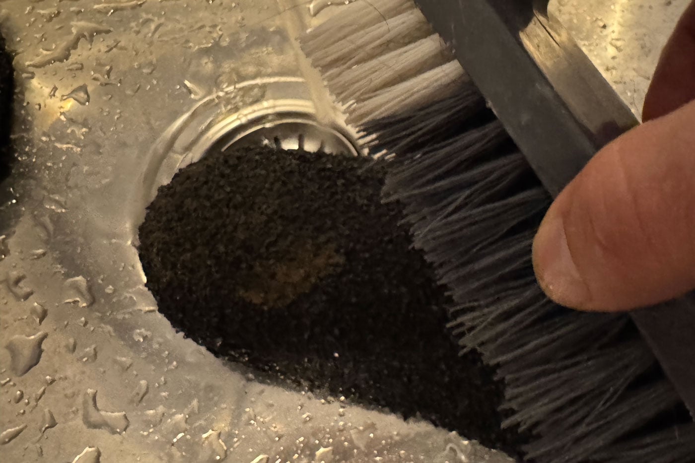 Skinners Comfort 2.0 Sock Shoe Review Brush scrubbing dark coffee grounds pooled around a stainless steel sink drain